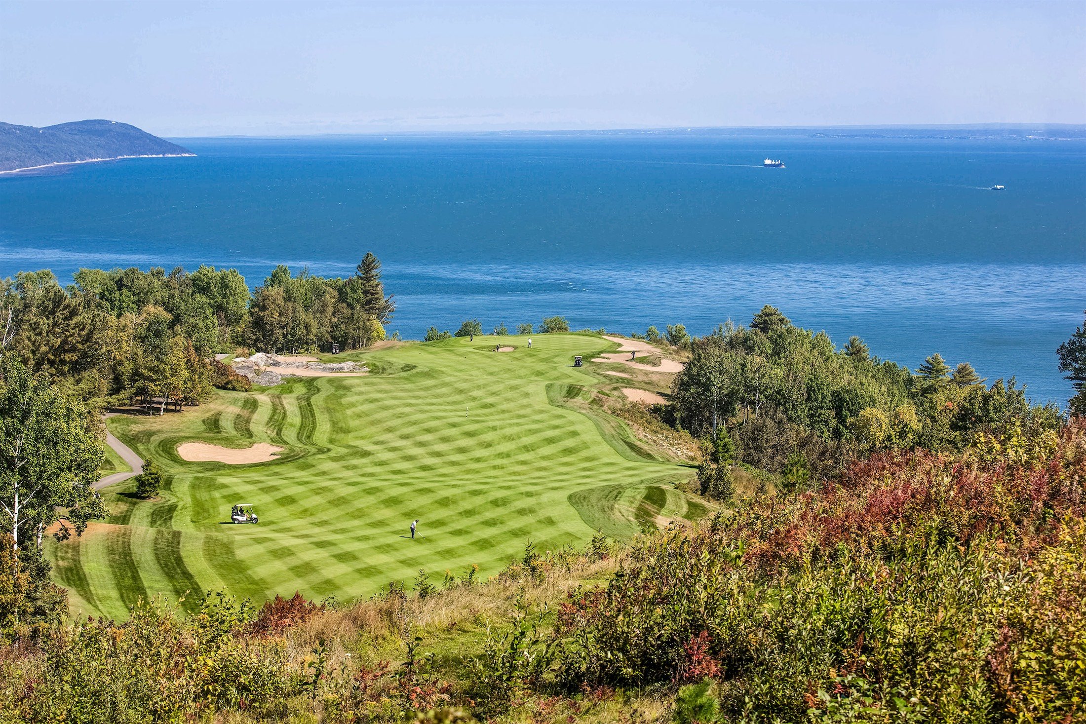 aerial shot of golf course next to a body of water