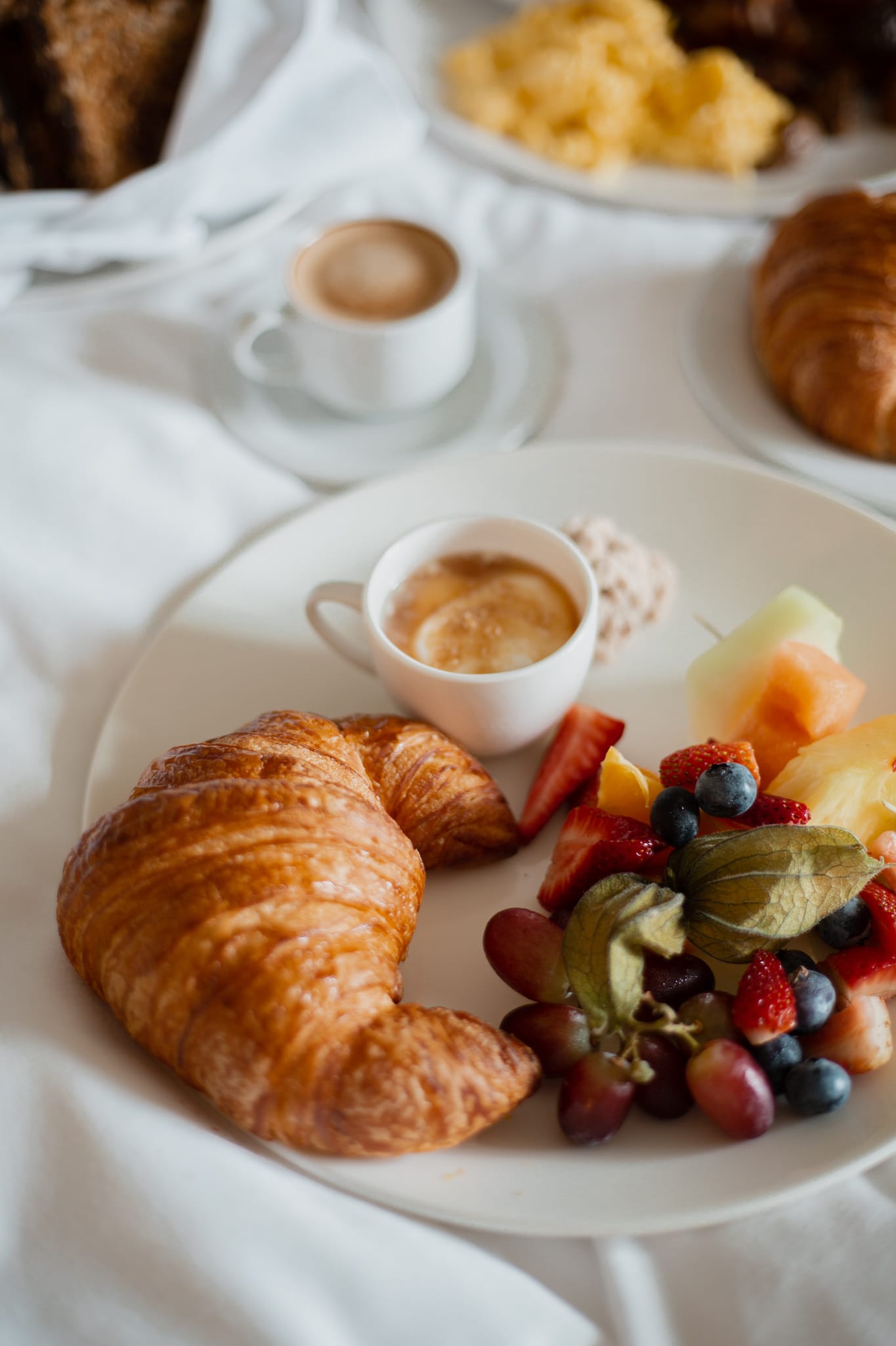 close up of a plate with a croissant and berries